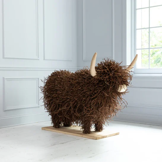 Furry brown sculpture of a Highland cow with wooden horns.